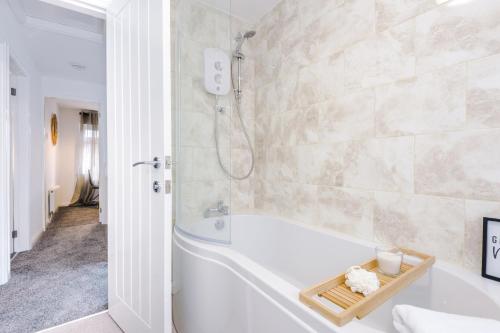 a white bathroom with a tub and a shower at Welcoming 3 bed home, 10 mins from Chester races and zoo in Saughall