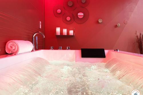 La salle de bains rouge est pourvue d'une baignoire avec de l'eau. dans l'établissement l'Orient-Express - Jacuzzi SPA - Parking - Loft, au Havre