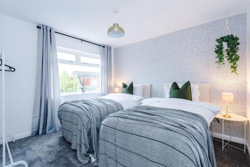 een slaapkamer met 2 bedden en een raam bij Welcoming 3 bed home, 10 mins from Chester races and zoo in Saughall