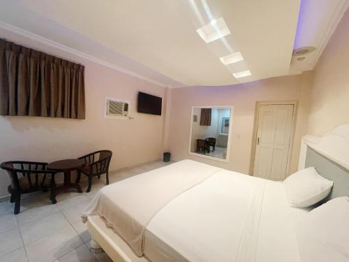 a bedroom with a white bed and a table at Hotel Pensión Anduriña in Panama City