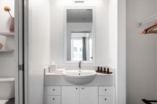 a white bathroom with a sink and a mirror at Locale Lofts The Gulch - Nashville in Nashville