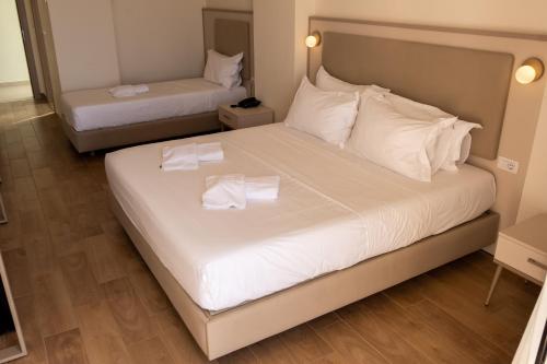 a bedroom with two beds with white sheets and towels at Fllad Resort & SPA Durres in Golem