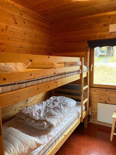 two bunk beds in a log cabin with a window at Stuga Huså Åre in Huså