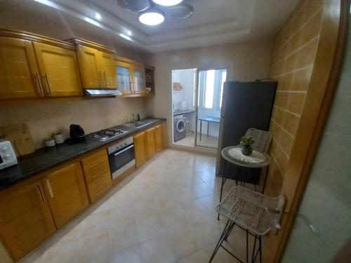 a kitchen with wooden cabinets and a black refrigerator at Appartement la perle de Nouaceur in Nouaceur