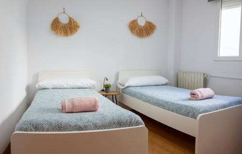 ein Schlafzimmer mit 2 Betten und rosa Kissen darauf in der Unterkunft Apartamento céntrico cerca de las estáciones in Santander