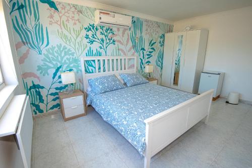 a bedroom with a bed with blue and pink wallpaper at By The Sea Guest House in San Andrés