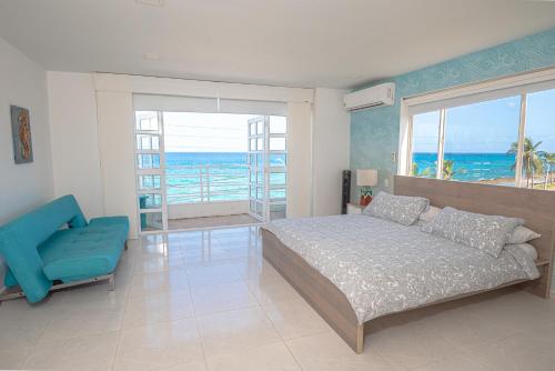 a bedroom with a bed and a blue chair at By The Sea Guest House in San Andrés