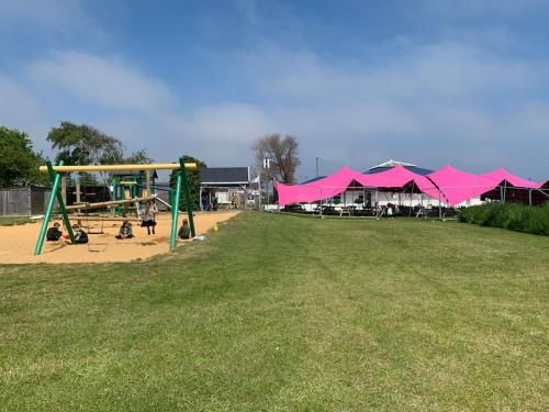 a park with a playground with pink umbrellas at Hugo's hideaway, Belle Aire Free WIFI in Hemsby