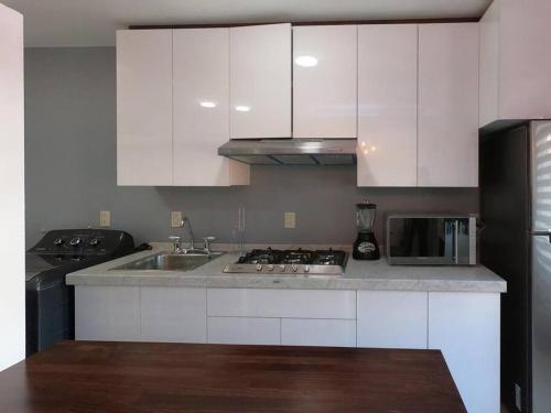 a kitchen with white cabinets and a sink and a refrigerator at San Felipe Apartament in Uruapan del Progreso