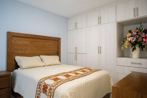 - une chambre avec un lit et un vase de fleurs dans l'établissement San Felipe Apartament, à Uruapan del Progreso