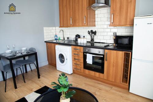 cocina con armarios de madera, mesa y lavavajillas en City Centre 2 Bed Flat Sleeps 3 for Work and Leisure with Free Wifi by Amazing Spaces Relocations Ltd en Warrington