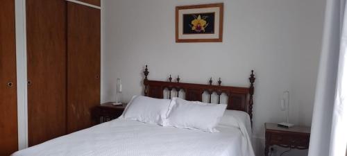 a bedroom with a bed with white sheets and pillows at Alojamiento El Coco in Puerto Madryn