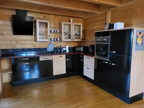 een keuken met zwarte apparatuur en houten wanden bij Blockhaus im Süden Deutschlands in Höchenschwand