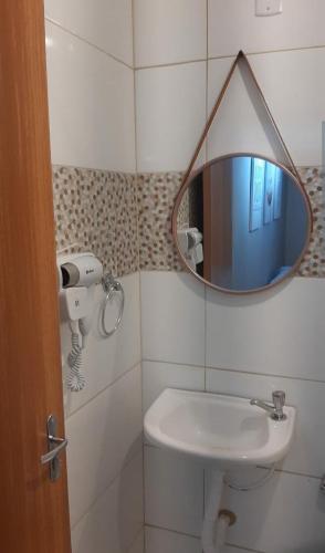 a bathroom with a mirror and a sink at Kitnet 1 - Apart-Hotel Premium in Sete Lagoas