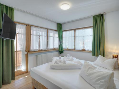 a bedroom with a large white bed with green curtains at Center Rooms & Apartments in Mayrhofen