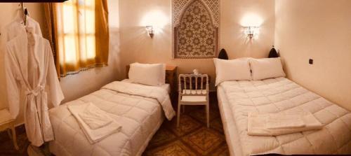 two beds in a small room with white sheets at Hotel la renaissance tata in Tatta