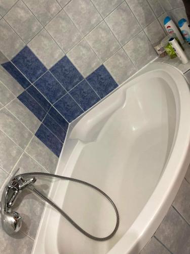 a white bath tub with a hose next to a tile floor at Szeged-Vár in Szeged