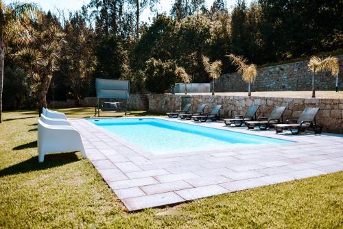 a swimming pool with lounge chairs next to a stone wall at Casa Lima Braga in Braga