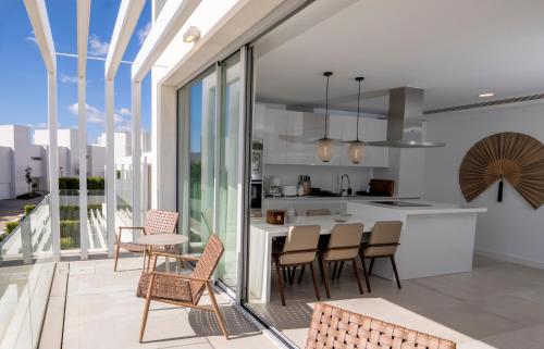 an open kitchen and dining area with chairs and a table at Villa La Perla Sotogrande - since 2022 - Sea View - 3 Bedrooms and Bathrooms - La Reserva Beach and Golf nearby in Sotogrande