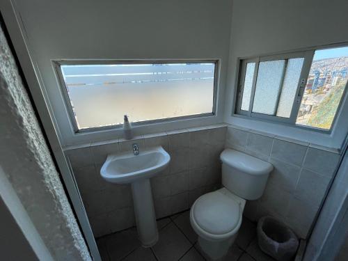 baño con lavabo y aseo y ventana en Hostal Recuerdos de Familia, en Valparaíso