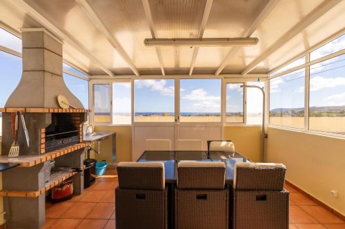 uma sala de jantar com mesa, cadeiras e janelas em Vista Mar em Porto Santo