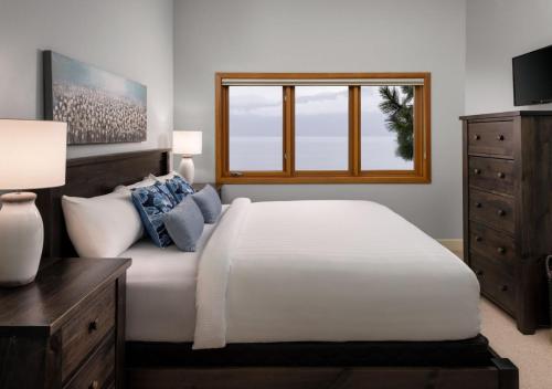a bedroom with a large white bed and a window at Outback Lakeside Vacation Homes in Vernon