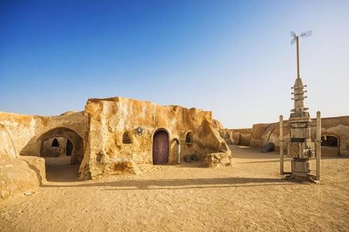 a stone building with a door in the desert at Résidence Le Ruisseau in Tozeur