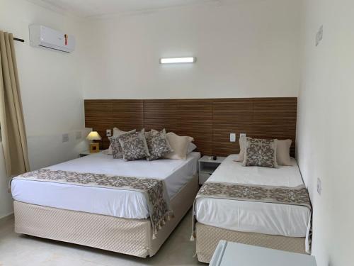 a bedroom with two beds and a headboard at Pousada Pé na Areia Guarujá in Guarujá