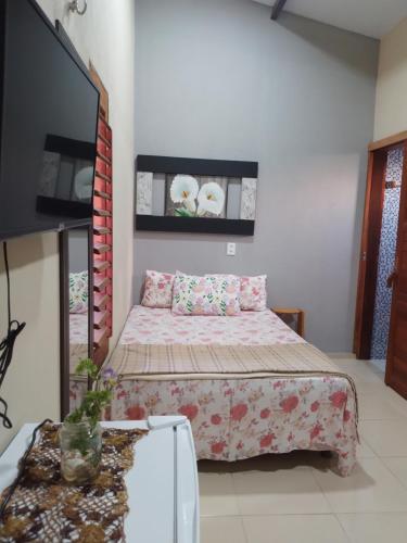 a bedroom with a bed and a flat screen tv at Vila Vintém Chalés in Praia de Moitas