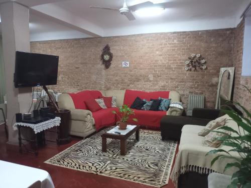 阿瓜斯－迪聖佩德羅的住宿－Pousada Líder，客厅设有红色沙发和砖墙