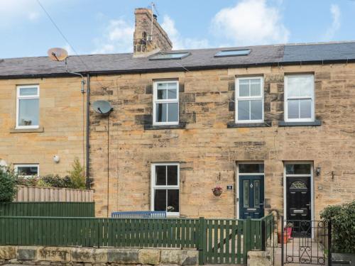 a brick house with a green fence in front of it at 19 Duke Street in Alnwick