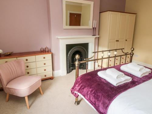 - une chambre avec un lit, une chaise et une cheminée dans l'établissement 19 Duke Street, à Alnwick