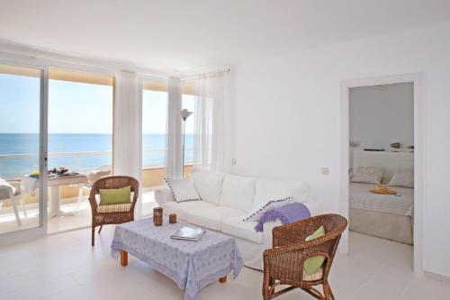 ein Wohnzimmer mit einer weißen Couch und Stühlen sowie Meerblick in der Unterkunft Apartamentos Golf Mar by La Costa Resort in Pals