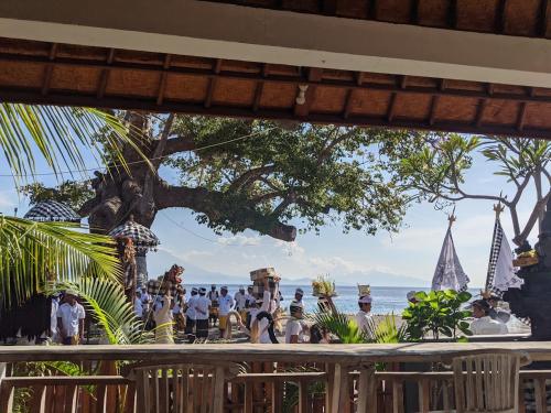 um grupo de pessoas de pé em uma varanda com vista para o oceano em Sarinah Beach - Bistro & Bungalow em Nusa Penida