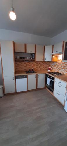 La cuisine est équipée de placards blancs et d'un four avec plaques de cuisson. dans l'établissement Apartment Kamýk, à Prague