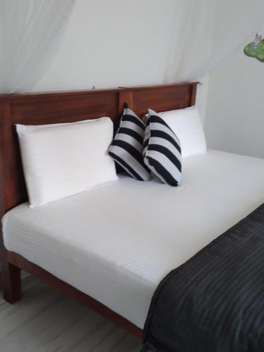 a bed with two black and white pillows on it at Holly House Homestay in Ella