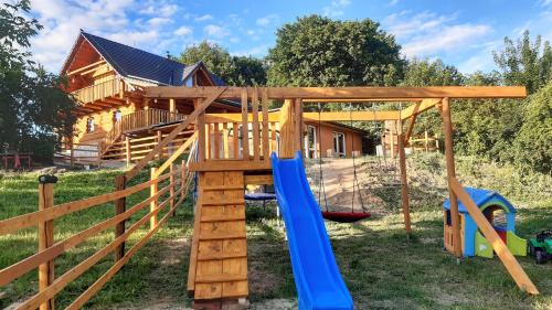 a wooden playground with a swing and a house at SrubNemo in Nemotice