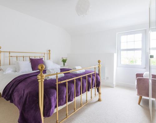 a bedroom with a bed with purple sheets and a window at Beehive Cottage in Port Isaac