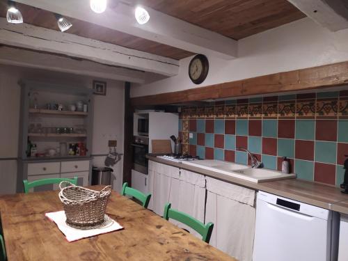 eine Küche mit einem Tisch und einer Uhr an der Wand in der Unterkunft La maison d'iréne in Soturac