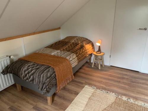 1 dormitorio con 1 cama y 1 mesa con lámpara en Het Slakkenhuisje en Maarn