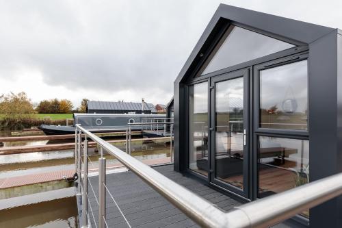 a black house with glass doors on a dock at Whimbrel in Tattenhall