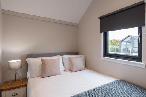 a bedroom with a white bed with a window at Whimbrel in Tattenhall