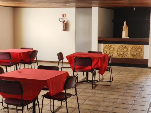 a room with red tables and chairs and a fireplace at Apartamento único na praia do Farol de Itapuã in Salvador