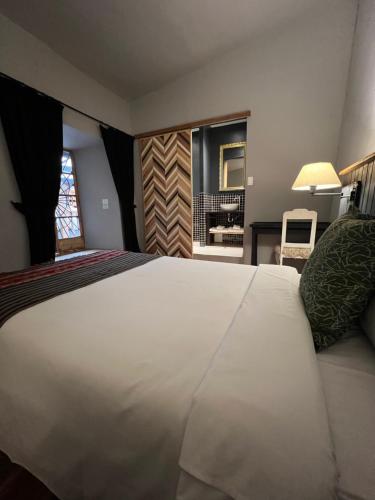 a bedroom with a large white bed and a bathroom at Casa Tunki in Cusco