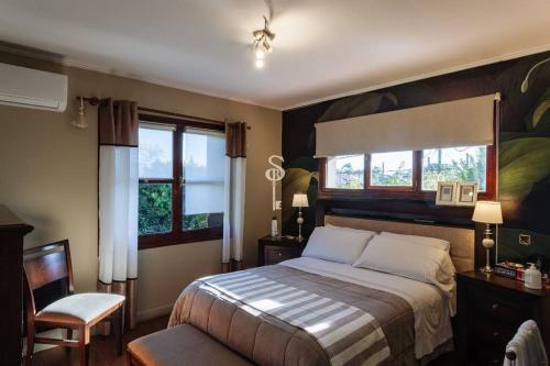 a bedroom with a bed and a chair and windows at Acogedor chalet a 5 minutos de las playas. in Mar del Plata