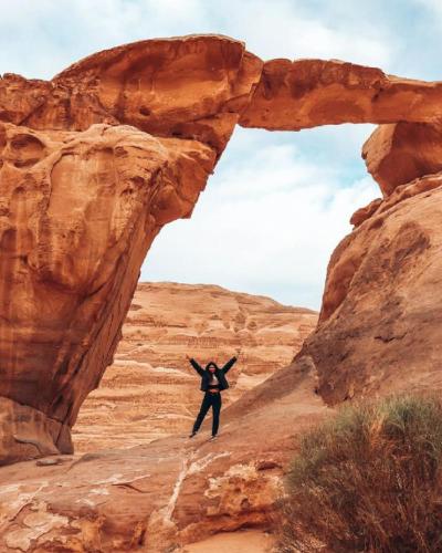 a man standing in front of an arch in the desert at Wadi Rum in Wadi Rum
