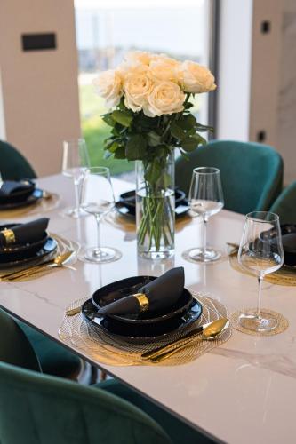 a table with a vase of flowers and plates and glasses at Villa Jadran in Podstrana