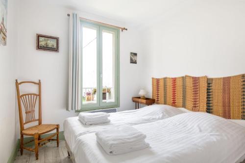 een slaapkamer met een bed, een stoel en een raam bij Appartement L'Îlot au centre du port de Saint Martin in Saint-Martin-de-Ré