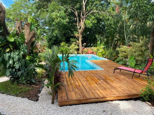 una terraza de madera con una silla junto a la piscina en Casa Mapache en Tamarindo