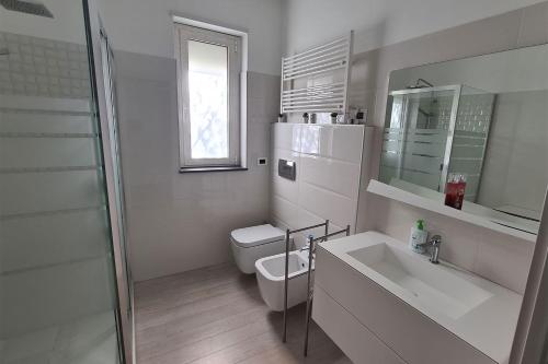 a white bathroom with a toilet and a sink at Villa con piscina in Leonforte